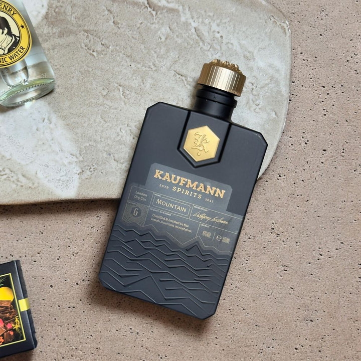 Ausgepacktes Gin Geschenkset mit Kaufmann Spirits Mountain Gin Thomas Henry Tonic Water Fenkart Gin Schokolade Sonnentor Pfeffer rosa ganz bio und ppd Gin Lover Cocktail Servietten