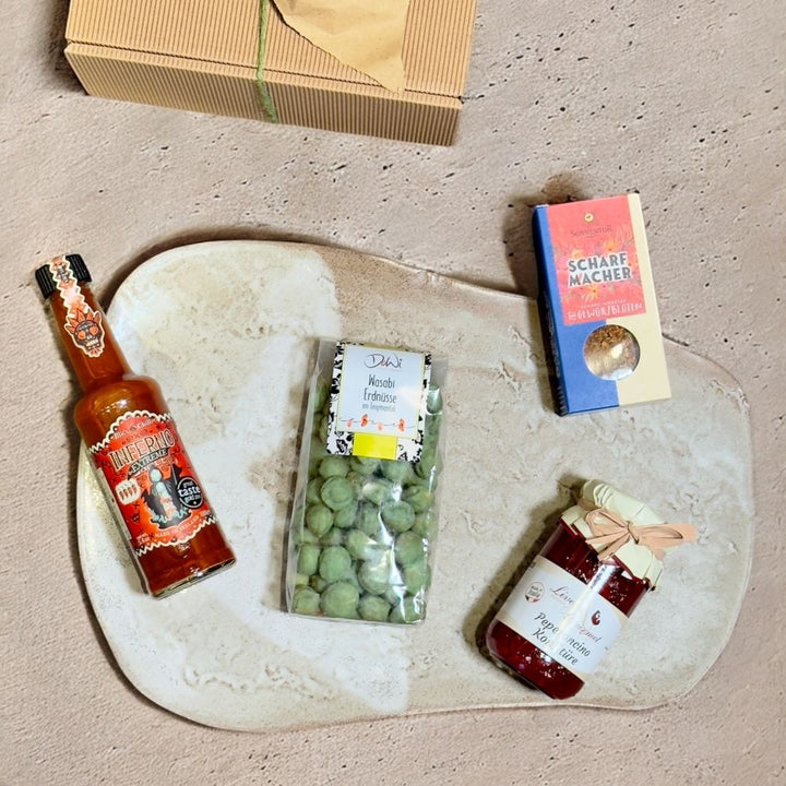 Ausgepackte Scharfe Geschenkbox mit DeWi Erdnüsse im Wasabi Teigmantel Mics Chilli Inferno Sauce Extreme Live Gourmet Peperoncino Konfitüre und Sonnentor Scharfmacher Gewürzblüten
