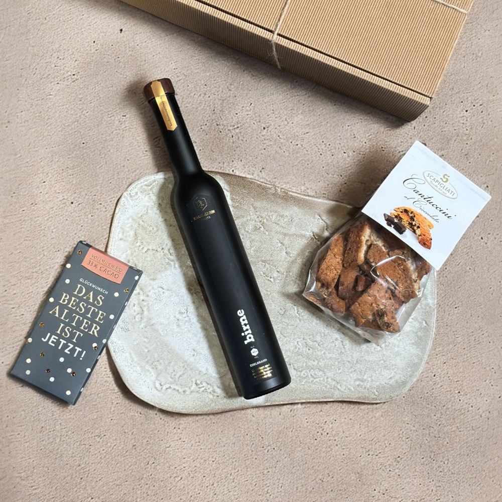Ausgepackte Edelbrand Geschenkbox mit Kaufmann Spirits Birne Edelbrand 350 ml Scapigliati Cantuccini al Cioccolato 150 g und Grafik Werkstatt Bio Schokolade Glückwunsch 80g