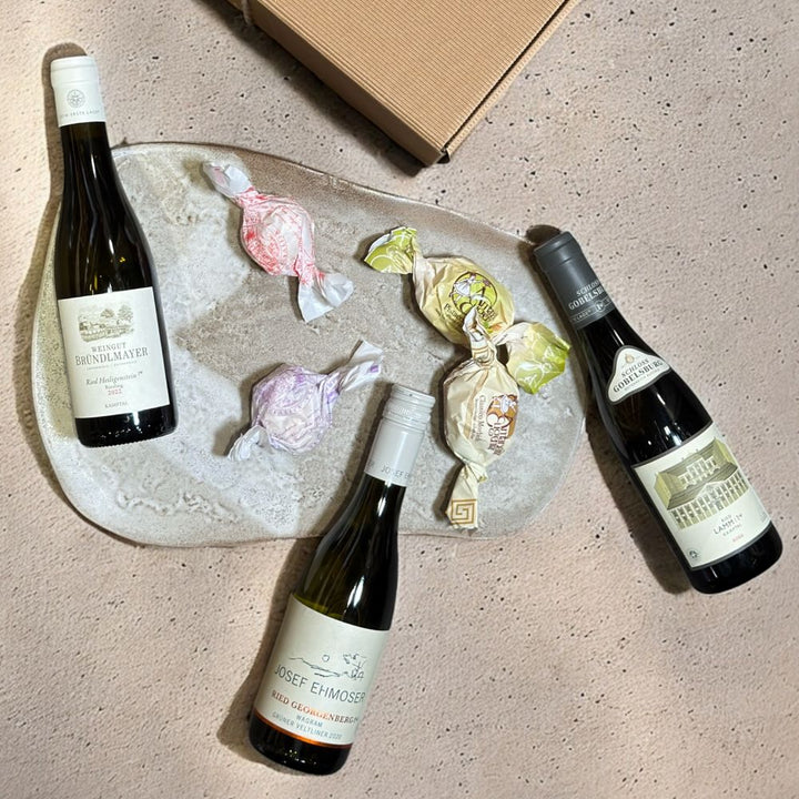 Ausgepackte Premium Weinbox Österreich mit Ehmoser Grüner Veltliner Georgenberg 2022 Bründlmayer Riesling Zöbinger Heiligenstein 2023 Schloss Gobelsburg Grüner Veltliner Ried Lamm 2022 Amaretti Eugenia und Brutti e Buoni Mandelgebäck