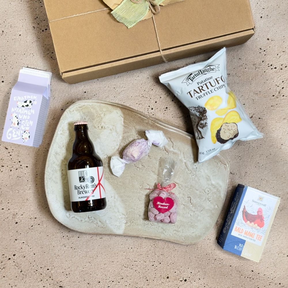 Ausgepackte Geschenkbox für Schwangere mit Rocky Rems Helles alkoholfrei Sonnentor Bald Mami Tee bio TartufLanghe Patatine Tartufo Truffle Chips Grafik Werkstatt Schaumzucker Kühe Einatmen SteirerKraft Himbeer Herzzuckerl und Brutti e Buoni