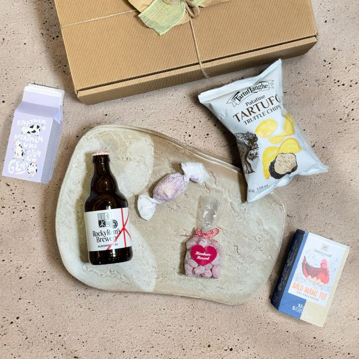 Ausgepackte Geschenkbox für Schwangere mit Rocky Rems Helles alkoholfrei Sonnentor Bald Mami Tee bio TartufLanghe Patatine Tartufo Truffle Chips Grafik Werkstatt Schaumzucker Kühe Einatmen SteirerKraft Himbeer Herzzuckerl und Brutti e Buoni