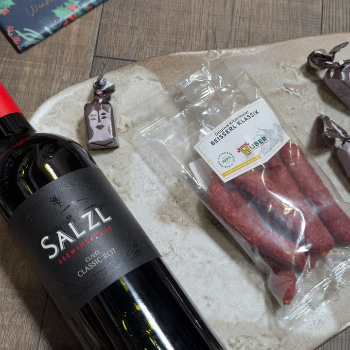 Ausgepackte Wein Geschenkbox Österreich mit Salzl Cuvée Classic Rot 2022 Metzgerei Huber Karreespeck Hubers Beisserl Prinz Alte Marille Fritz Felix Mini Schüttelbrot DeWi Schneemandeln Quaranta Florentine Grafik Werkstatt Schokolade ppd Christmas embossed green Servietten und Tartufo schwarz