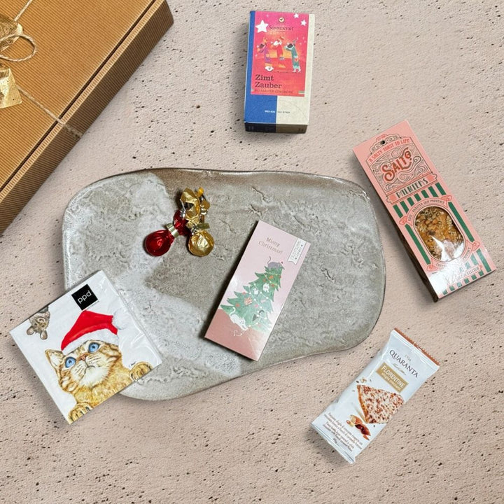 Ausgepackte Weihnachten Geschenkbox mit Salto Palmiers Käse Kräuter der Provence Venchi rote goldene Weihnachtskometen Quaranta Florentine weiße Schoko Karamell Grafik Werkstatt Fruchtgummi Merry Christmas Sonnentor Zimt Zauber Kräuter Gewürzteemischung und ppd Who are you Servietten