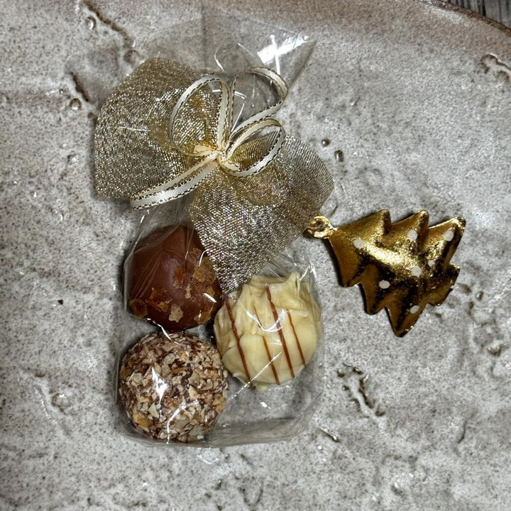 Ausgepacktes Pralinen Geschenkset Weihnachten mit 10 x 3 Pralinen im Säckchen verpackt mit weihnachtlichem Anhänger und Schleife sowie Metall Weihnachtsmotive hängend weiß silber gold sortiert